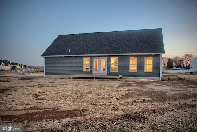 back house at dusk with french doors and a wooden deck