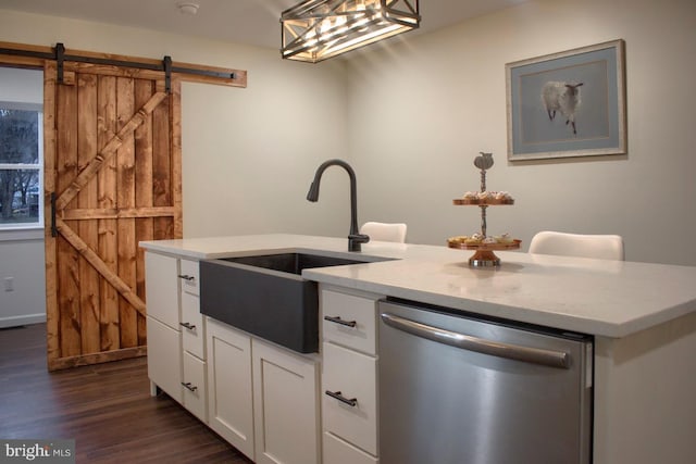 kitchen with stainless steel dishwasher, a barn door, decorative light fixtures, dark hardwood / wood-style floors, and white cabinetry