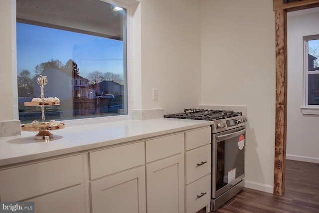 kitchen with light stone countertops, white cabinets, high end stainless steel range oven, and dark wood-type flooring