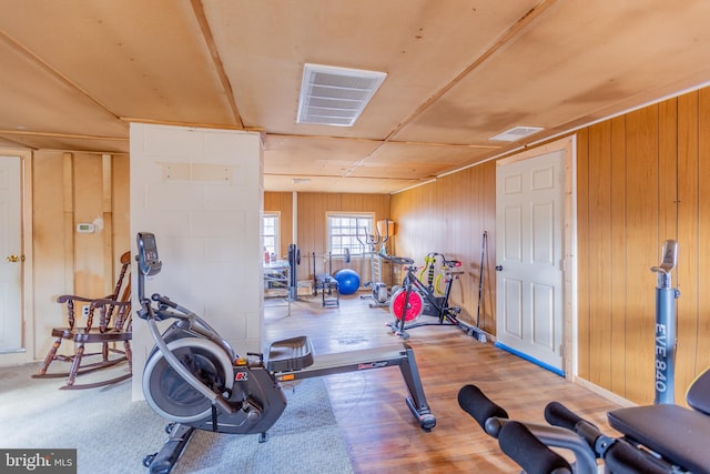 workout room featuring wood-type flooring and wood walls