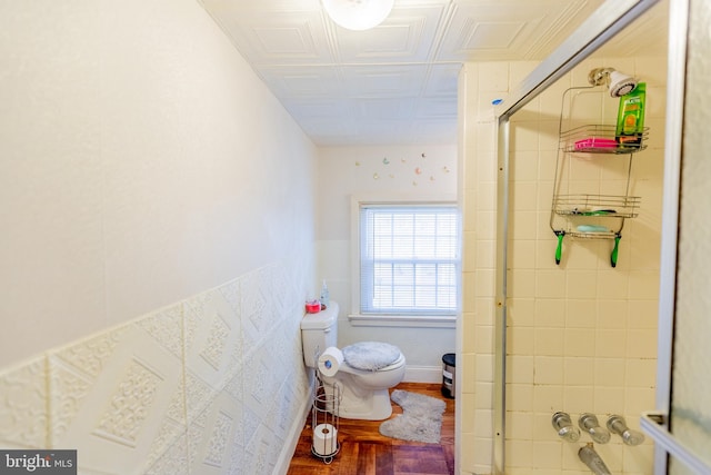 bathroom with hardwood / wood-style flooring, toilet, and a shower with door