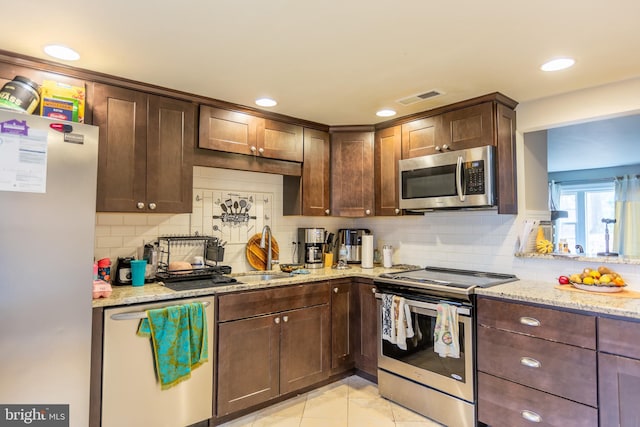 123 E Street Rd, West Chester, PA 19382 - kitchen featuring appliances with stainless steel finishes, tasteful backsplash, light stone counters, dark brown cabinetry, and light tile patterned floors