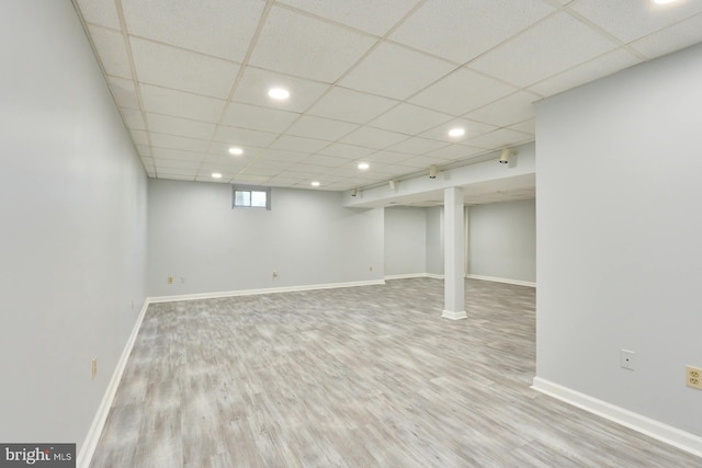 basement featuring a paneled ceiling and light wood-type flooring