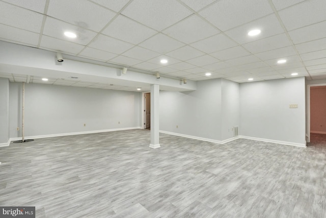 basement featuring a paneled ceiling and hardwood / wood-style flooring