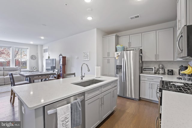 kitchen featuring sink, stainless steel appliances, dark hardwood / wood-style flooring, an island with sink, and gray cabinets