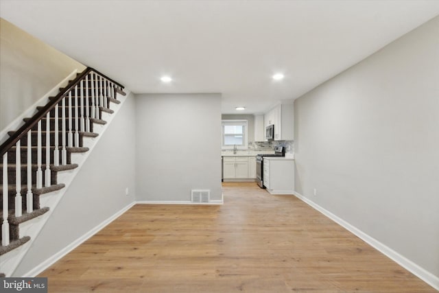 unfurnished living room featuring light hardwood / wood-style floors and sink