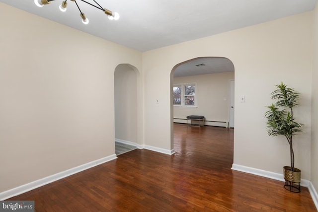 unfurnished room featuring a chandelier, dark wood-type flooring, and a baseboard heating unit