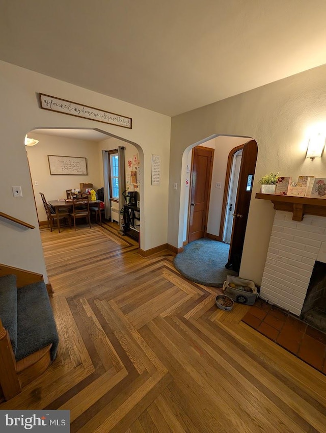 living room featuring baseboards, arched walkways, and a fireplace