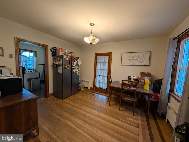 dining space featuring radiator, wood finished floors, and baseboards