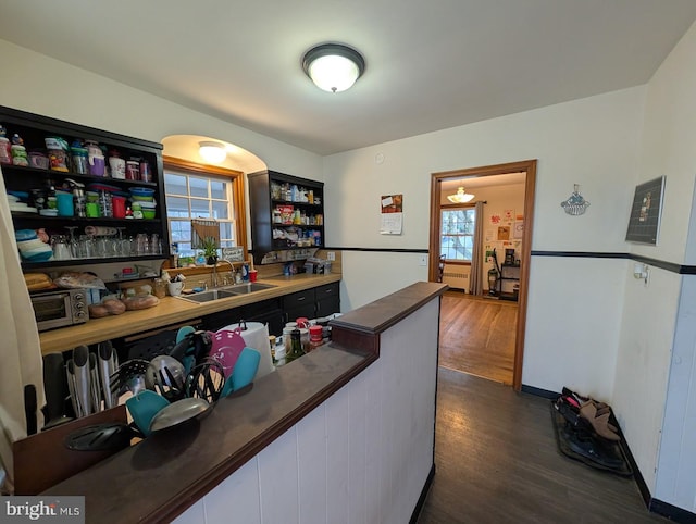 kitchen featuring dark countertops, a sink, dark wood-type flooring, white cabinetry, and open shelves