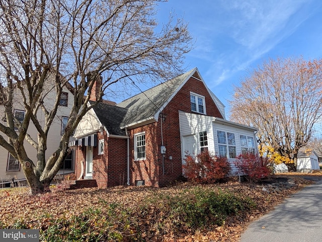 view of property exterior with brick siding and a shingled roof