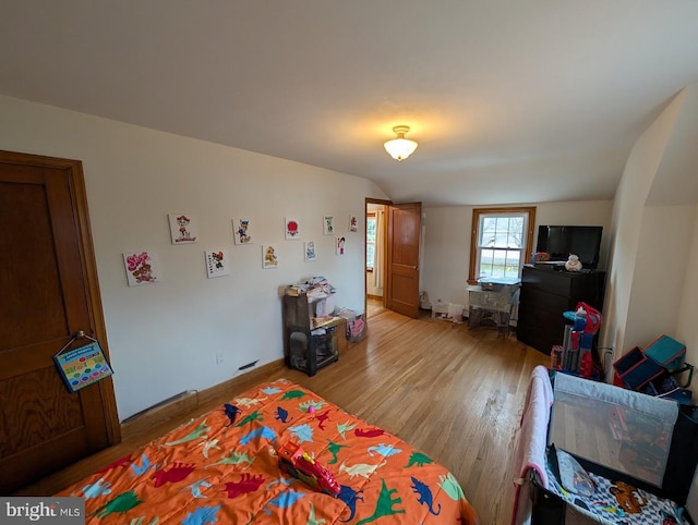 bedroom featuring vaulted ceiling, baseboards, and light wood finished floors