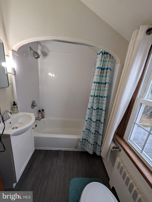 bathroom featuring toilet, radiator heating unit, shower / tub combo, wood finished floors, and vanity