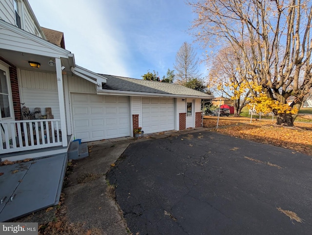 view of property exterior with a garage, brick siding, and roof with shingles