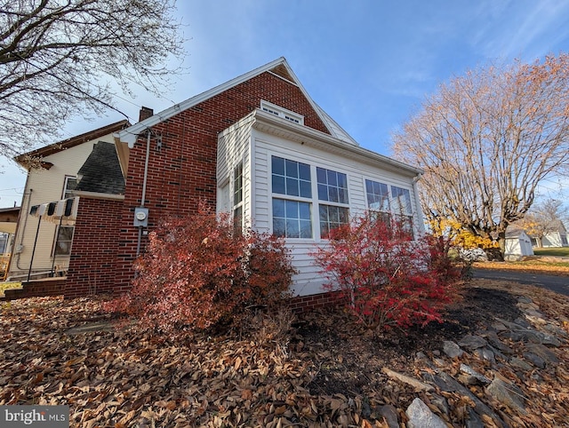 view of side of property featuring brick siding and a chimney