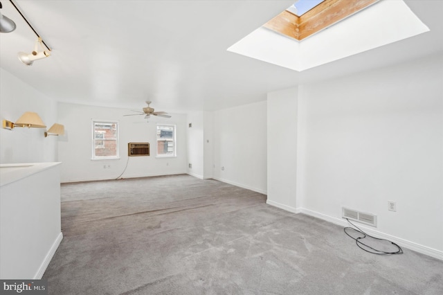 unfurnished living room with a skylight, ceiling fan, and light colored carpet