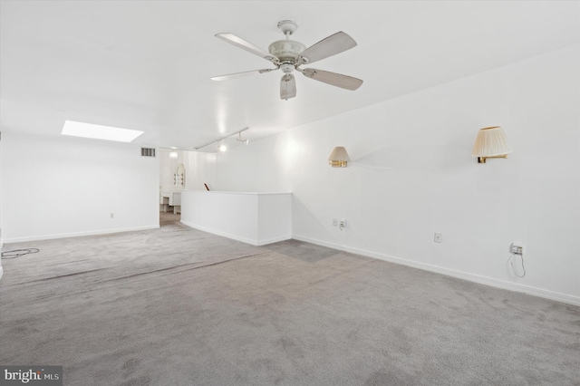 carpeted spare room with ceiling fan and a skylight