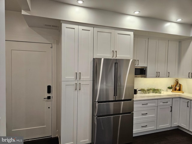 kitchen featuring white cabinetry, decorative backsplash, dark wood-type flooring, and stainless steel appliances