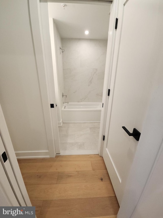 bathroom featuring wood finished floors and bathing tub / shower combination