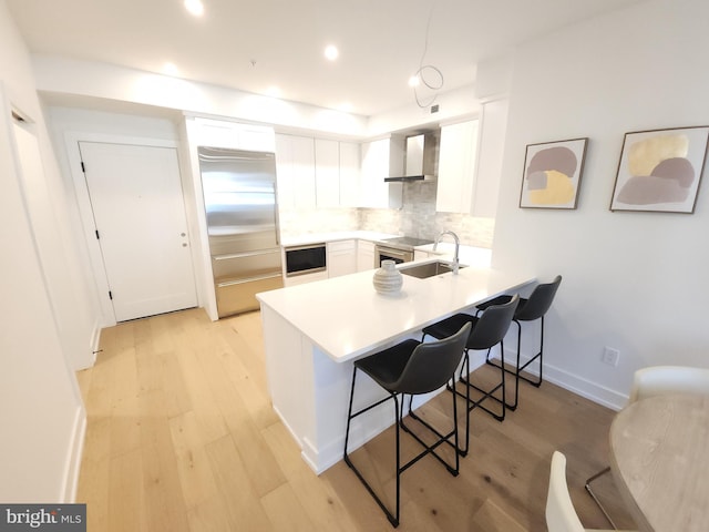 8610 Evergreen Pl Unit 202, Philadelphia, PA 19118 - kitchen featuring built in fridge, a sink, a peninsula, a breakfast bar area, and light wood finished floors