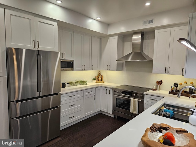 kitchen featuring light countertops, visible vents, appliances with stainless steel finishes, a sink, and wall chimney range hood