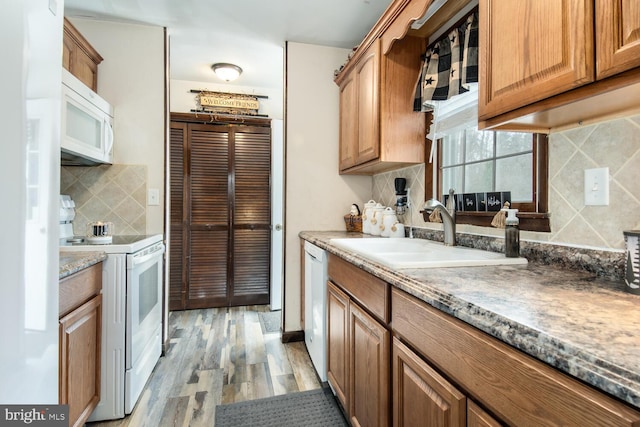 kitchen featuring backsplash, sink, white appliances, and light hardwood / wood-style flooring