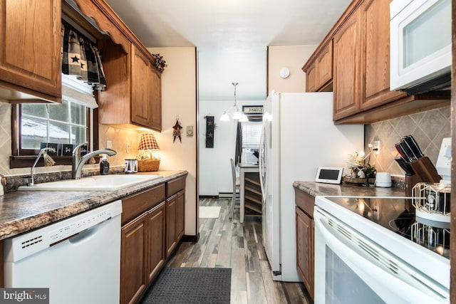 kitchen featuring decorative backsplash, sink, white appliances, and pendant lighting