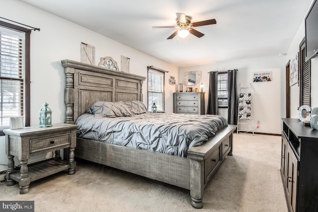 bedroom featuring ceiling fan, light colored carpet, and multiple windows