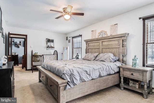 bedroom featuring ceiling fan, light colored carpet, and multiple windows