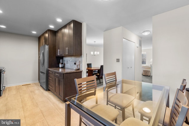 kitchen with tasteful backsplash, dark stone countertops, pendant lighting, dark brown cabinets, and appliances with stainless steel finishes