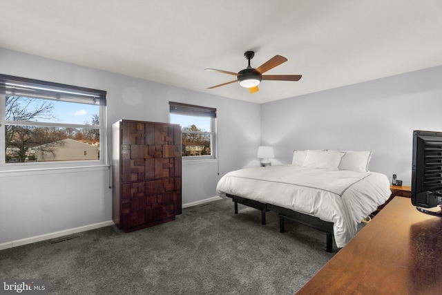 bedroom featuring dark colored carpet, multiple windows, and ceiling fan