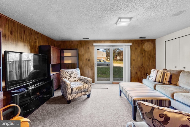 carpeted living room featuring a textured ceiling and wooden walls