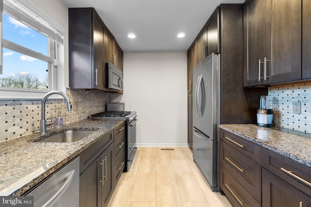 kitchen with decorative backsplash, light stone counters, sink, and stainless steel appliances