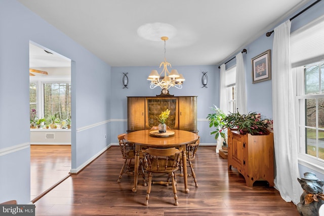 dining space featuring dark hardwood / wood-style flooring, a healthy amount of sunlight, and an inviting chandelier