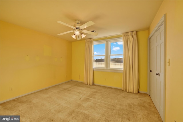 empty room featuring ceiling fan and light carpet