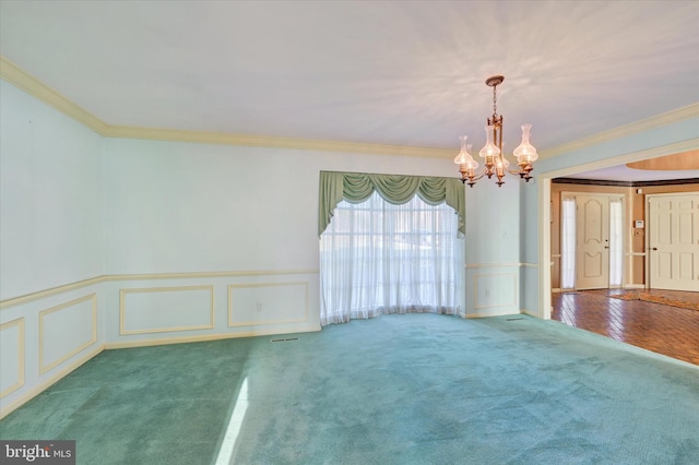 carpeted empty room featuring a chandelier and crown molding