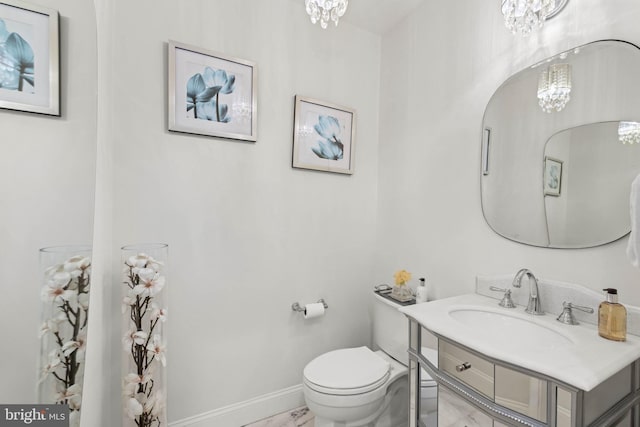 bathroom with toilet, an inviting chandelier, and sink