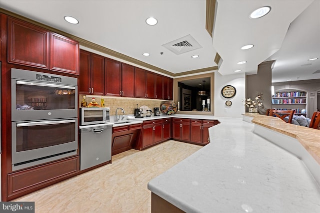 kitchen with sink, stainless steel appliances, tasteful backsplash, light stone counters, and kitchen peninsula