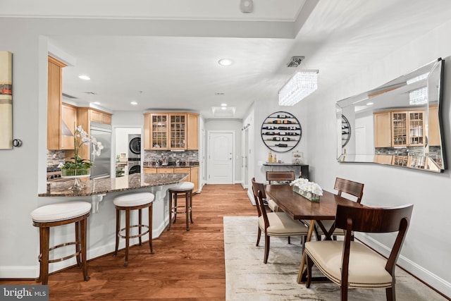 dining area featuring stacked washer and dryer and hardwood / wood-style flooring