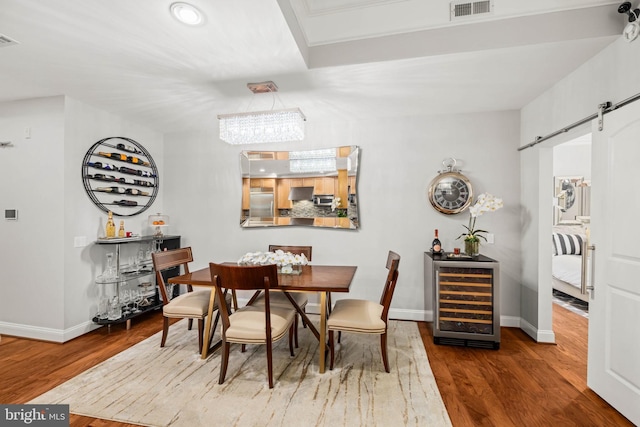 dining space with hardwood / wood-style flooring, a barn door, and wine cooler