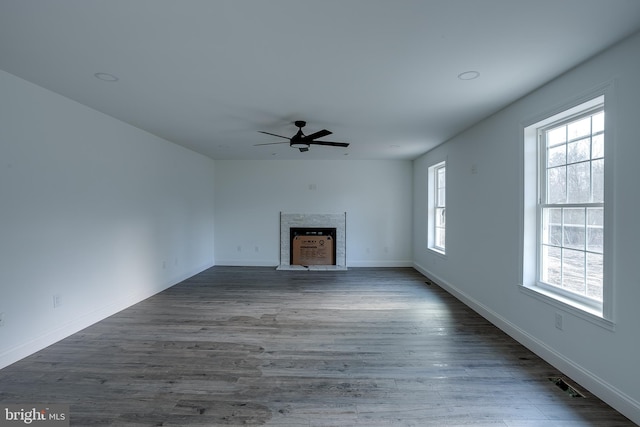 unfurnished living room featuring plenty of natural light, ceiling fan, and dark hardwood / wood-style flooring