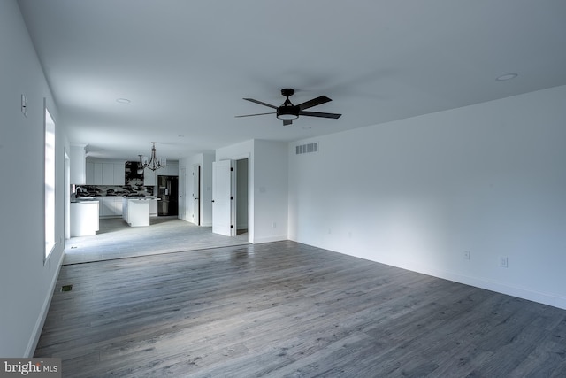 unfurnished living room with ceiling fan with notable chandelier and light wood-type flooring