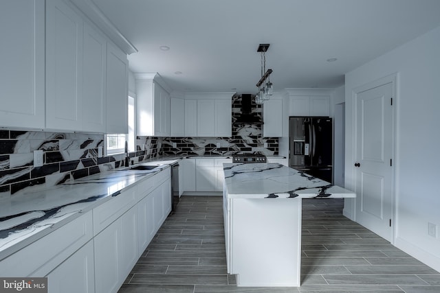 kitchen with a center island, premium range hood, black appliances, light stone countertops, and white cabinetry