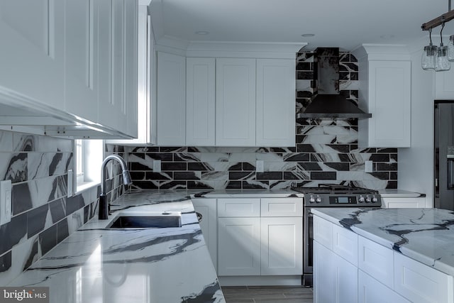 kitchen with wall chimney exhaust hood, light stone countertops, white cabinetry, and stainless steel appliances