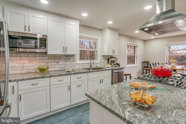 kitchen featuring white cabinets, sink, island range hood, light stone counters, and stainless steel appliances