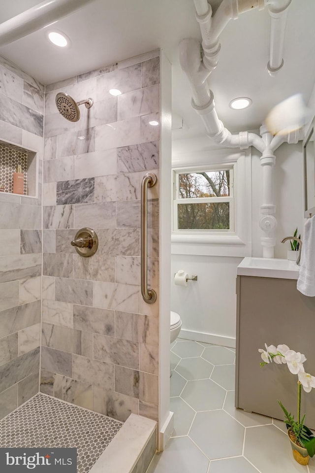 bathroom featuring tile patterned floors, toilet, a tile shower, and sink