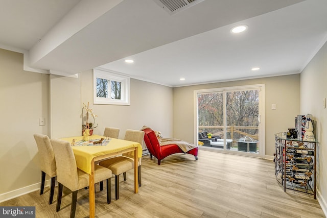 dining room with light hardwood / wood-style floors and crown molding