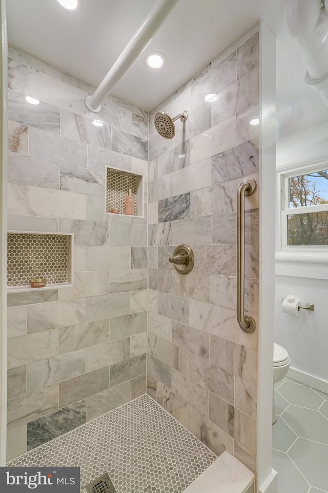 bathroom featuring a tile shower and toilet