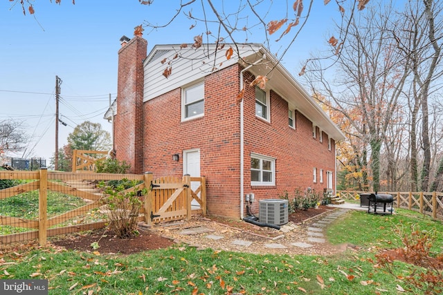 rear view of house featuring a yard and central AC unit