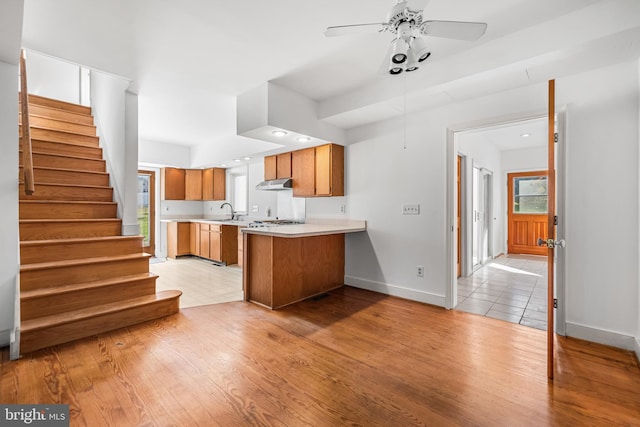 kitchen featuring kitchen peninsula, light hardwood / wood-style flooring, ceiling fan, and sink